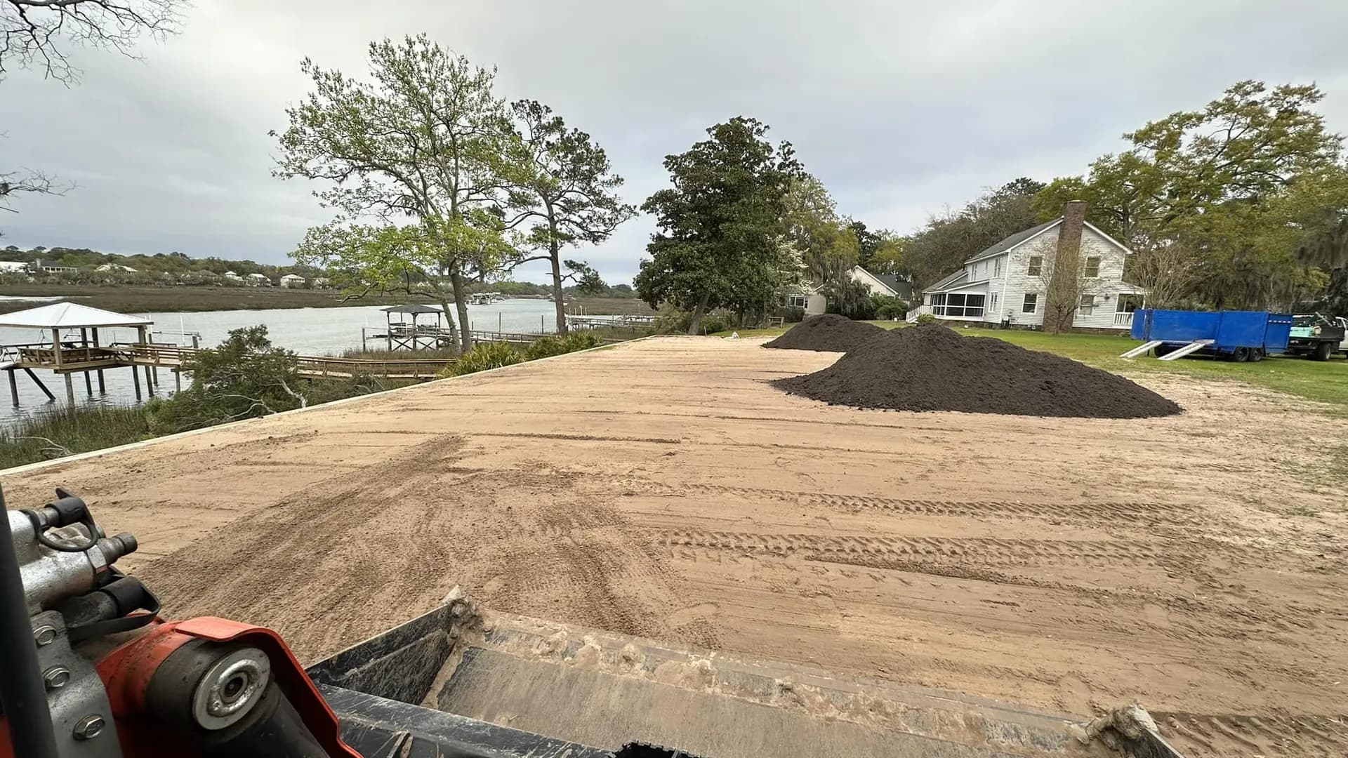 Freshly graded waterfront property with fill material ready for placement