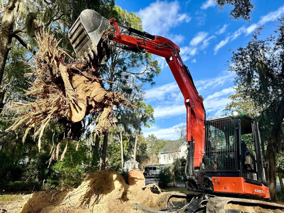 Equipment removing a stump beside a residential property
